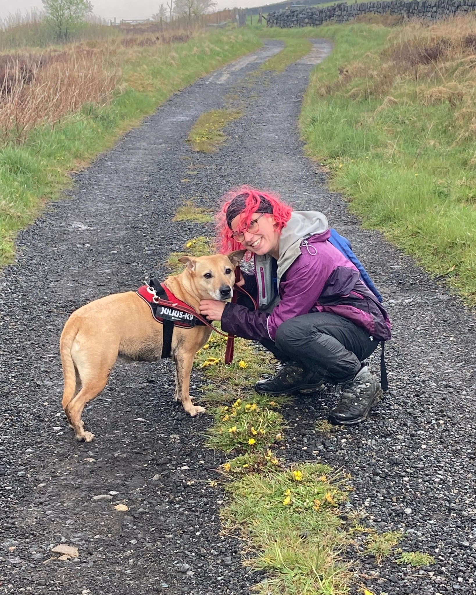 Charlotte crouching with a dog on a countryside track